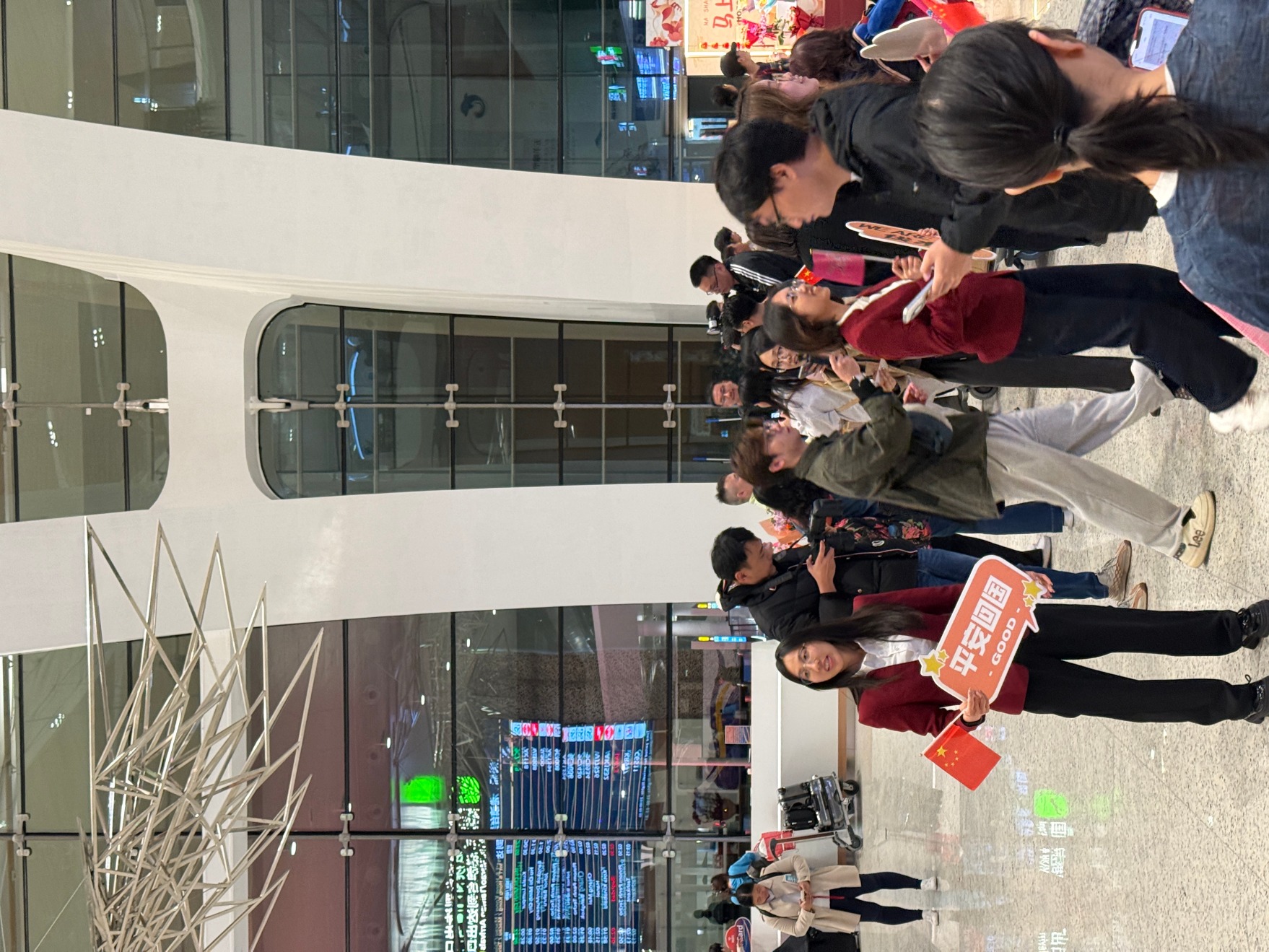 广州白云机场接机口，有人举牌平安回国。