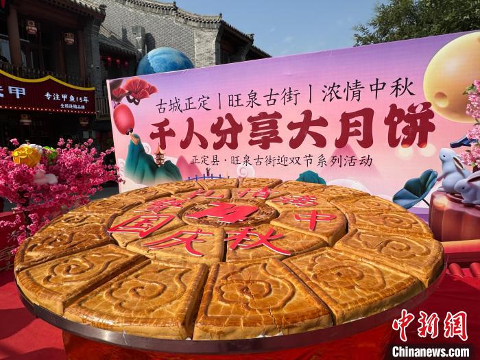 众多市民和游客手拿月饼券,在指定位置有序排队等待领取超级大月饼.